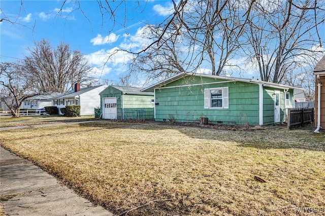 view of side of home with a garage, fence, a yard, an outdoor structure, and crawl space