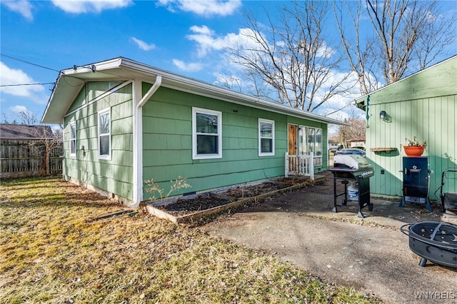 view of side of home with crawl space and fence