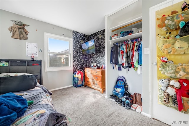 carpeted bedroom featuring a closet and baseboards