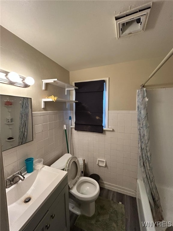 full bathroom with vanity, wood finished floors, tile walls, toilet, and shower / tub combo with curtain