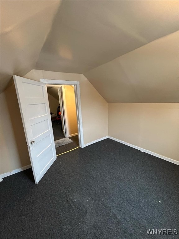 bonus room with lofted ceiling, baseboards, and dark colored carpet