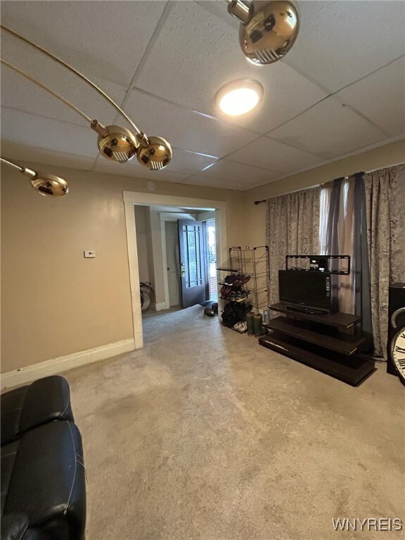 living room with carpet flooring, a paneled ceiling, and baseboards