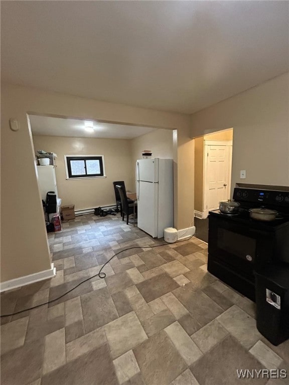 interior space featuring baseboards, black / electric stove, stone finish floor, and freestanding refrigerator