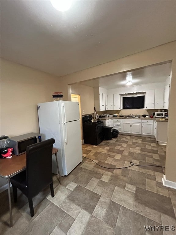 kitchen featuring freestanding refrigerator, a sink, white cabinets, black electric range, and stainless steel microwave