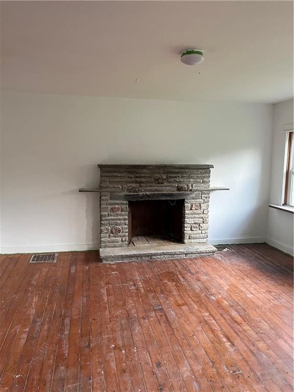 unfurnished living room featuring visible vents, a fireplace, baseboards, and wood-type flooring