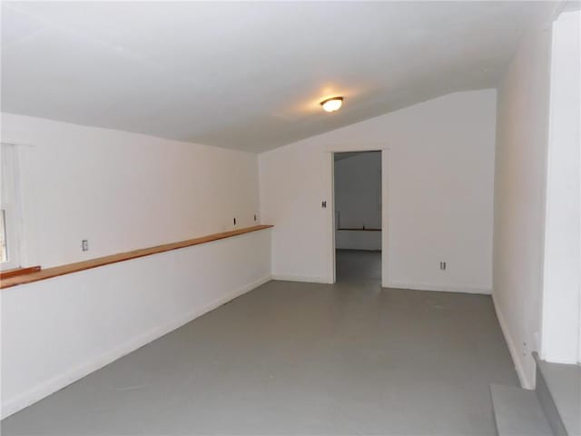 unfurnished room with baseboards, lofted ceiling, and concrete floors