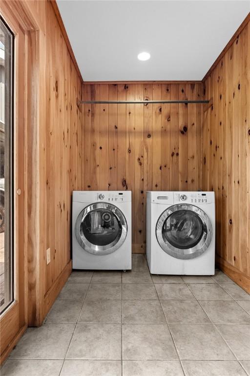 7317 County Highway 33, Kortright, NY 13739 - washroom featuring washer and dryer, light tile patterned flooring, laundry area, and wood walls