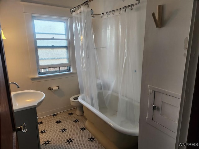 full bathroom featuring tile patterned floors, shower / bath combo with shower curtain, toilet, baseboards, and vanity