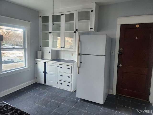 kitchen featuring plenty of natural light, white cabinets, and freestanding refrigerator