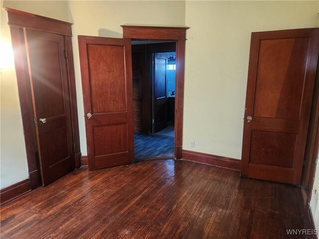 unfurnished bedroom with dark wood finished floors and baseboards