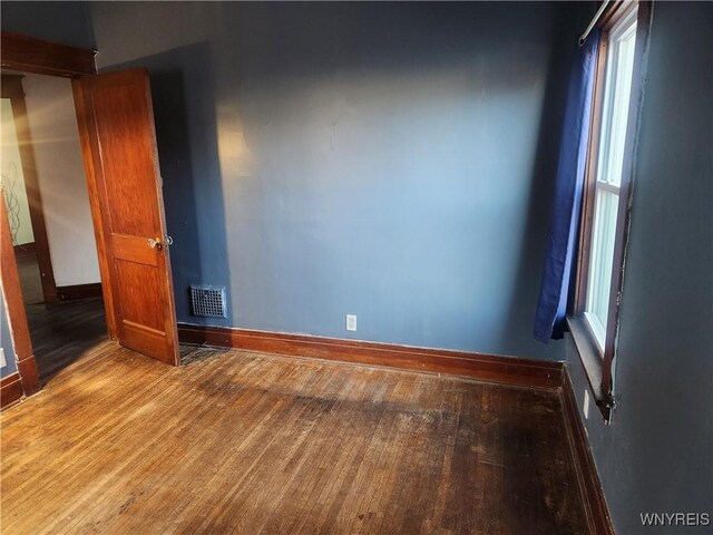 spare room with visible vents, baseboards, and hardwood / wood-style floors