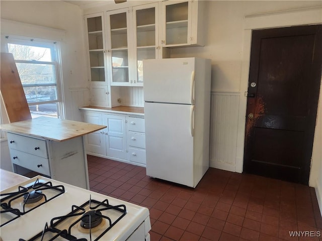 kitchen featuring a wainscoted wall, white cabinets, white appliances, and glass insert cabinets