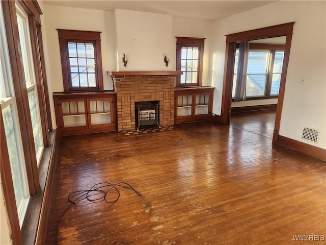 unfurnished living room featuring visible vents, baseboards, a fireplace, and hardwood / wood-style flooring