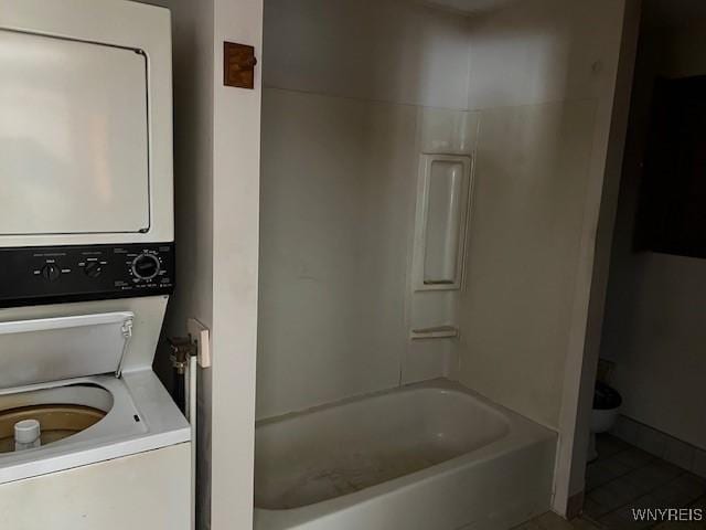 bathroom featuring estacked washer and dryer, toilet, tile patterned flooring, and bathing tub / shower combination
