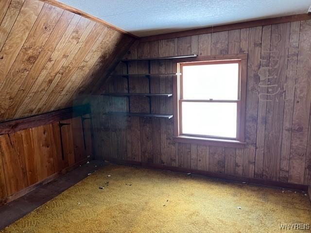 bonus room featuring wooden walls, vaulted ceiling, and baseboards
