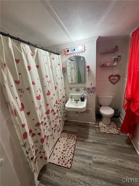 163 E 9th St, Oswego-City, NY 13126 - bathroom with a textured ceiling, curtained shower, wood finished floors, a sink, and toilet