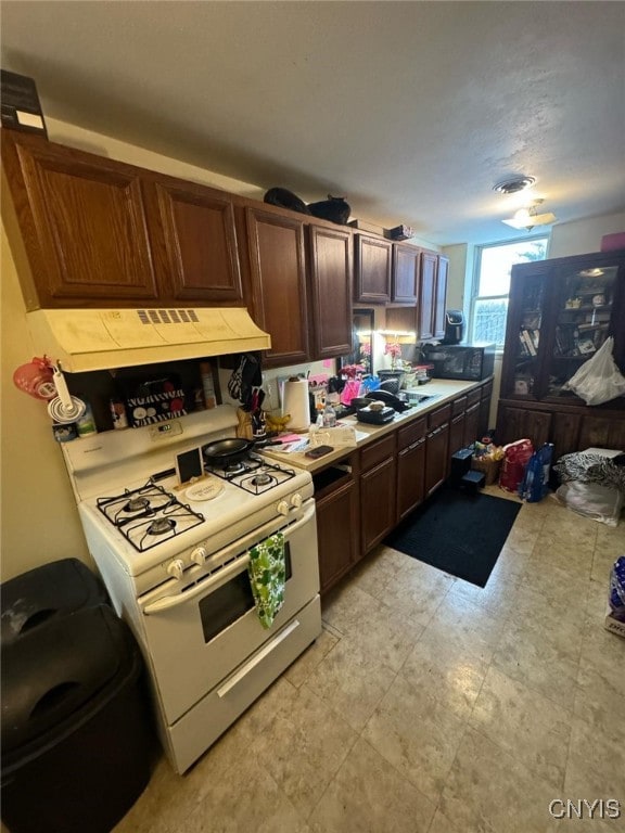 163 E 9th St, Oswego-City, NY 13126 - kitchen with light countertops, white range with gas cooktop, dark brown cabinets, and extractor fan