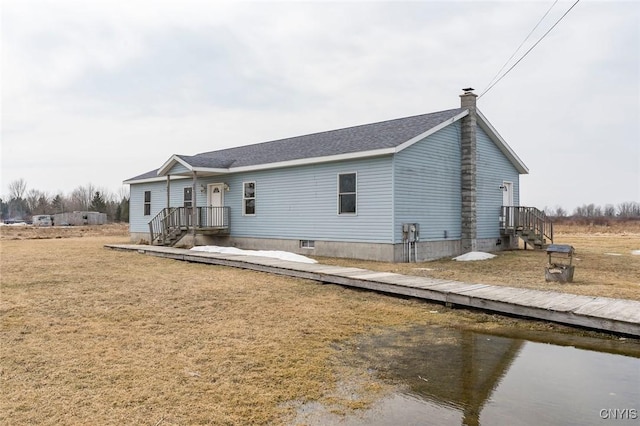 rear view of property featuring roof with shingles and a water view
