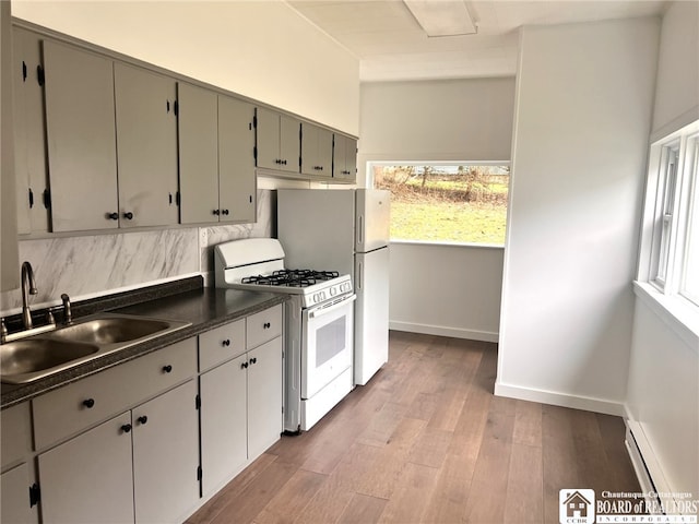 298 S Main St, Jamestown, NY 14701 - kitchen featuring dark countertops, a baseboard heating unit, white range with gas stovetop, a wealth of natural light, and a sink