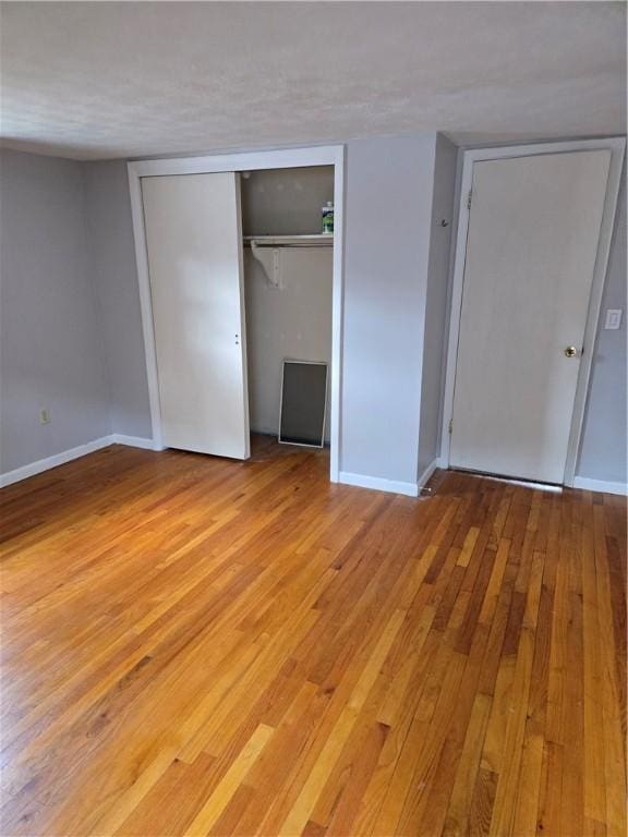 unfurnished bedroom featuring baseboards, a closet, and light wood-style floors