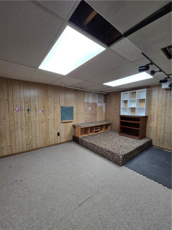 interior space featuring baseboards, wooden walls, and a paneled ceiling
