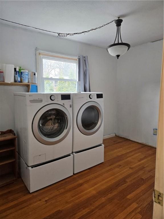 laundry room with washer and clothes dryer, wood finished floors, and laundry area
