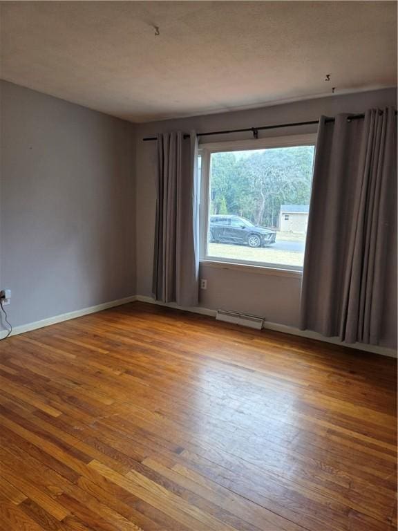 unfurnished room with baseboards, visible vents, and wood-type flooring