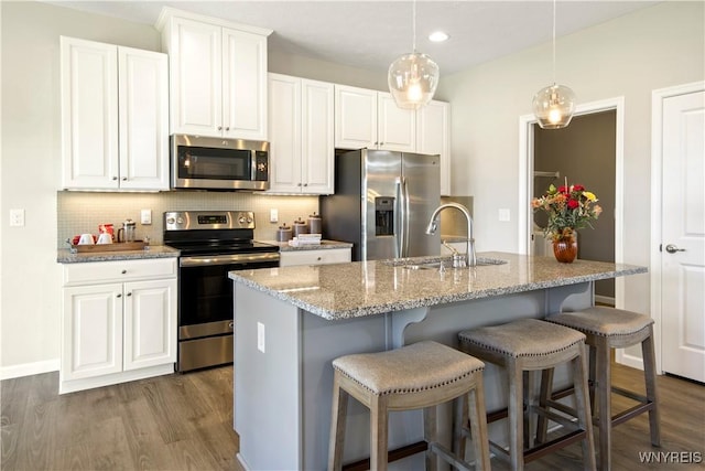 kitchen featuring a sink, dark wood finished floors, stainless steel appliances, white cabinets, and decorative backsplash