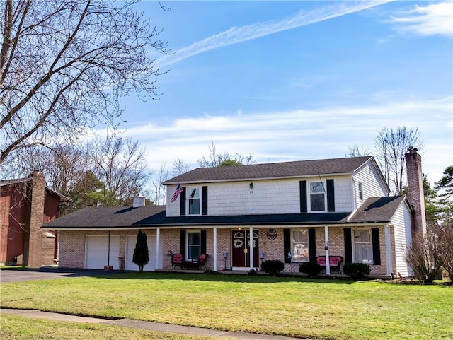 traditional-style home with aphalt driveway, a garage, covered porch, and a front yard