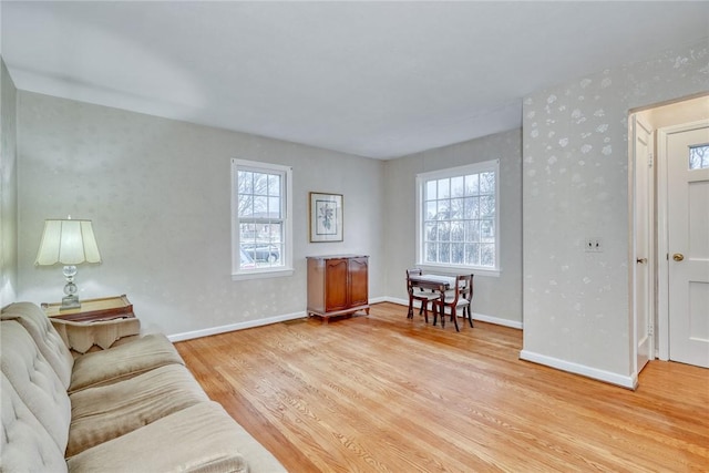 sitting room featuring light wood-style flooring, baseboards, and a wealth of natural light