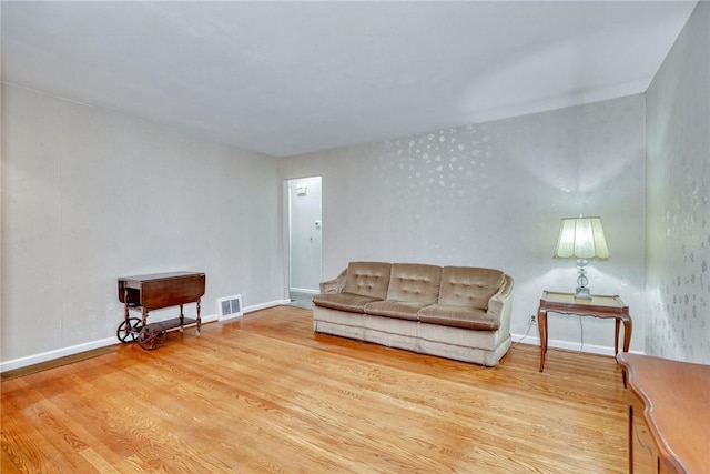 living area with visible vents, baseboards, and wood finished floors