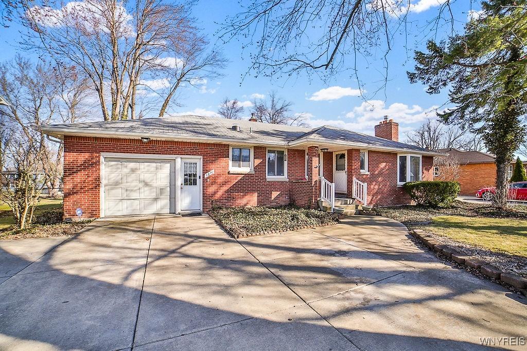 ranch-style house with brick siding, a chimney, concrete driveway, and a garage