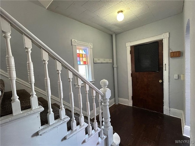 foyer featuring baseboards, wood finished floors, and stairs