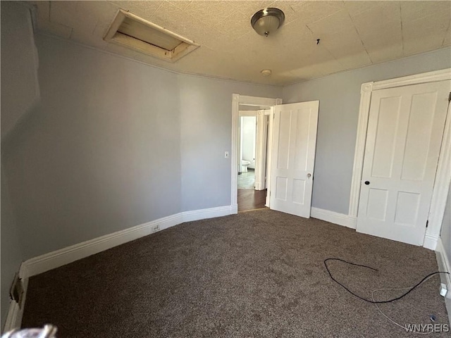 unfurnished bedroom with baseboards, attic access, and carpet