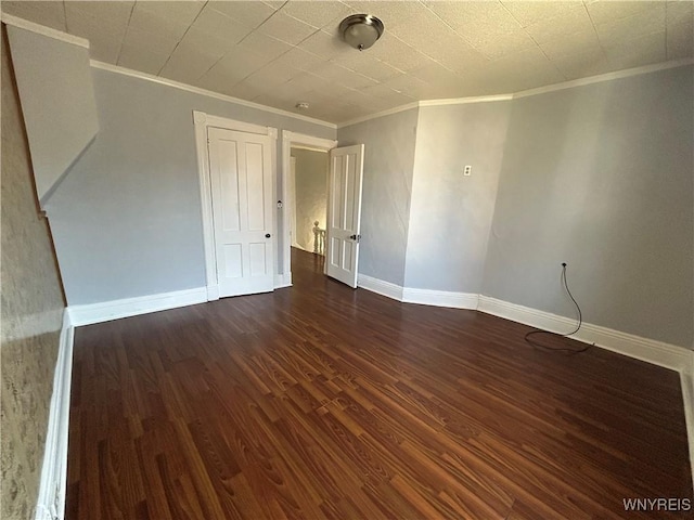empty room with crown molding, baseboards, and wood finished floors