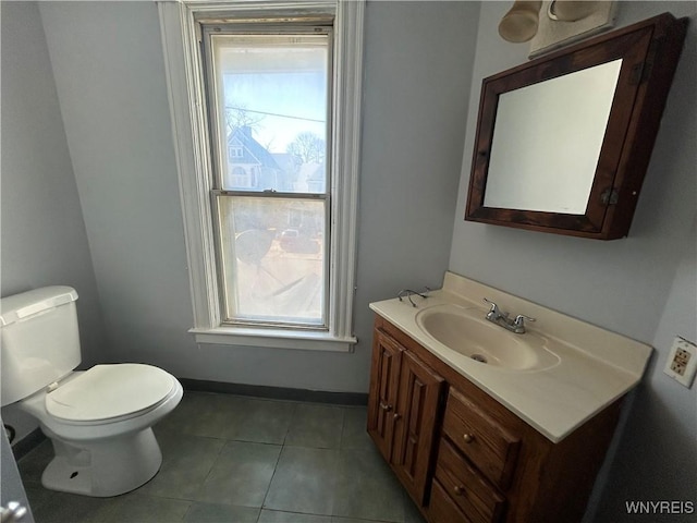 half bathroom featuring tile patterned floors, baseboards, toilet, and vanity