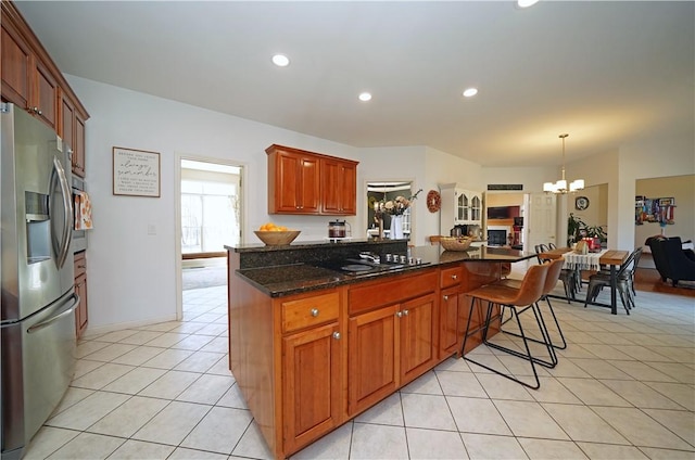 kitchen featuring dark stone countertops, light tile patterned flooring, recessed lighting, stainless steel fridge, and a chandelier