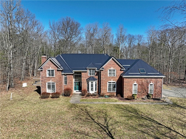 traditional home featuring a front lawn, brick siding, and metal roof