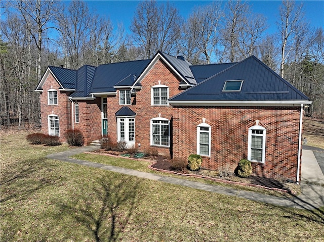 view of front of house featuring brick siding, a standing seam roof, metal roof, and a front lawn