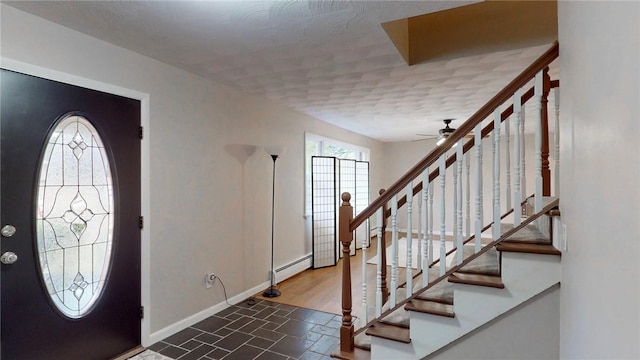 entrance foyer with baseboards, a baseboard heating unit, stairway, and a ceiling fan