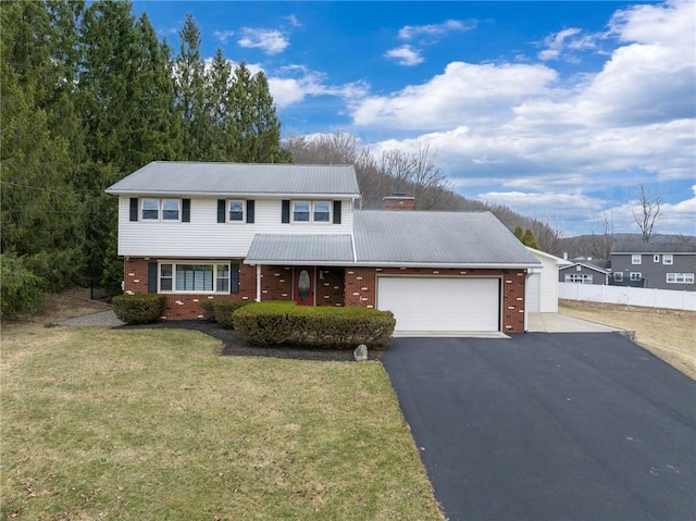 traditional-style house featuring an attached garage, a chimney, a front yard, brick siding, and driveway
