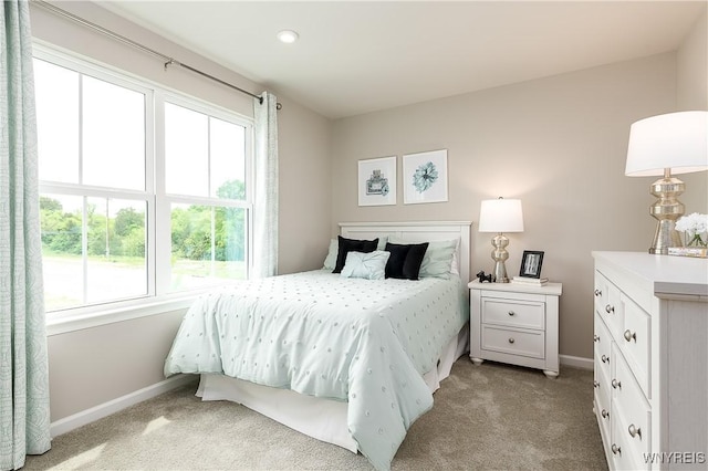 bedroom featuring multiple windows, baseboards, and light carpet