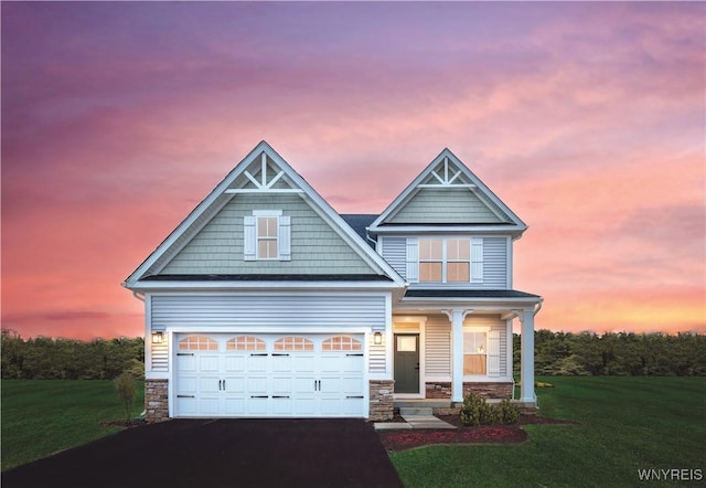 view of front of home with a front lawn, a porch, stone siding, and driveway