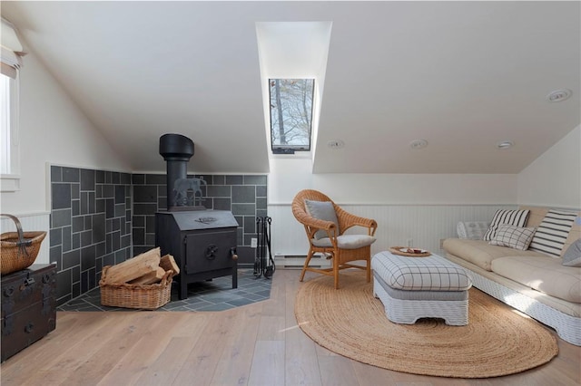 196 Wellington Ln, Springfield, NY 13326 - living room featuring hardwood / wood-style flooring, a baseboard heating unit, lofted ceiling, wainscoting, and a wood stove