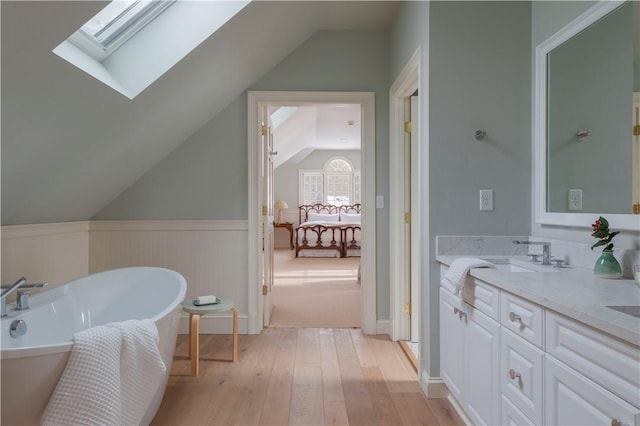196 Wellington Ln, Springfield, NY 13326 - bathroom with lofted ceiling, a soaking tub, wood-type flooring, a skylight, and double vanity