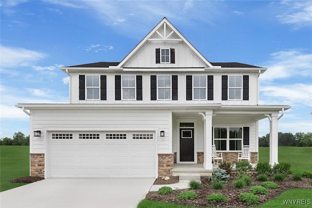 view of front of house with board and batten siding, a front lawn, concrete driveway, covered porch, and stone siding
