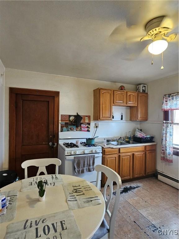 406 S George St, Rome-Inside, NY 13440 - kitchen featuring a sink, a baseboard heating unit, gas range gas stove, and brown cabinetry