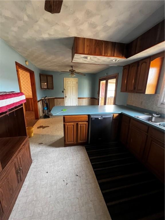 kitchen with ceiling fan, black dishwasher, brown cabinets, a peninsula, and a sink