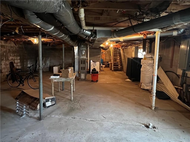 unfinished basement featuring electric panel, stairway, and heating unit