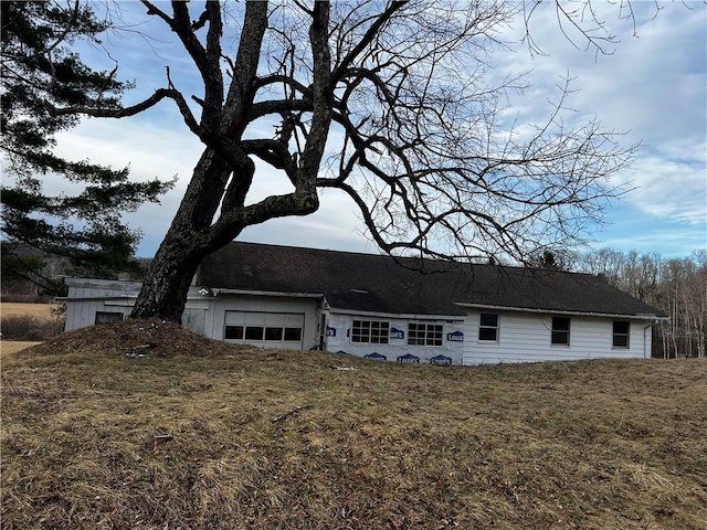 view of front of house with a garage, a front lawn, and a shingled roof